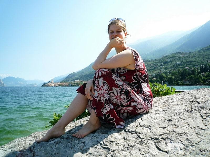 Julia von Tofunatives sitzt auf einem Stein am See