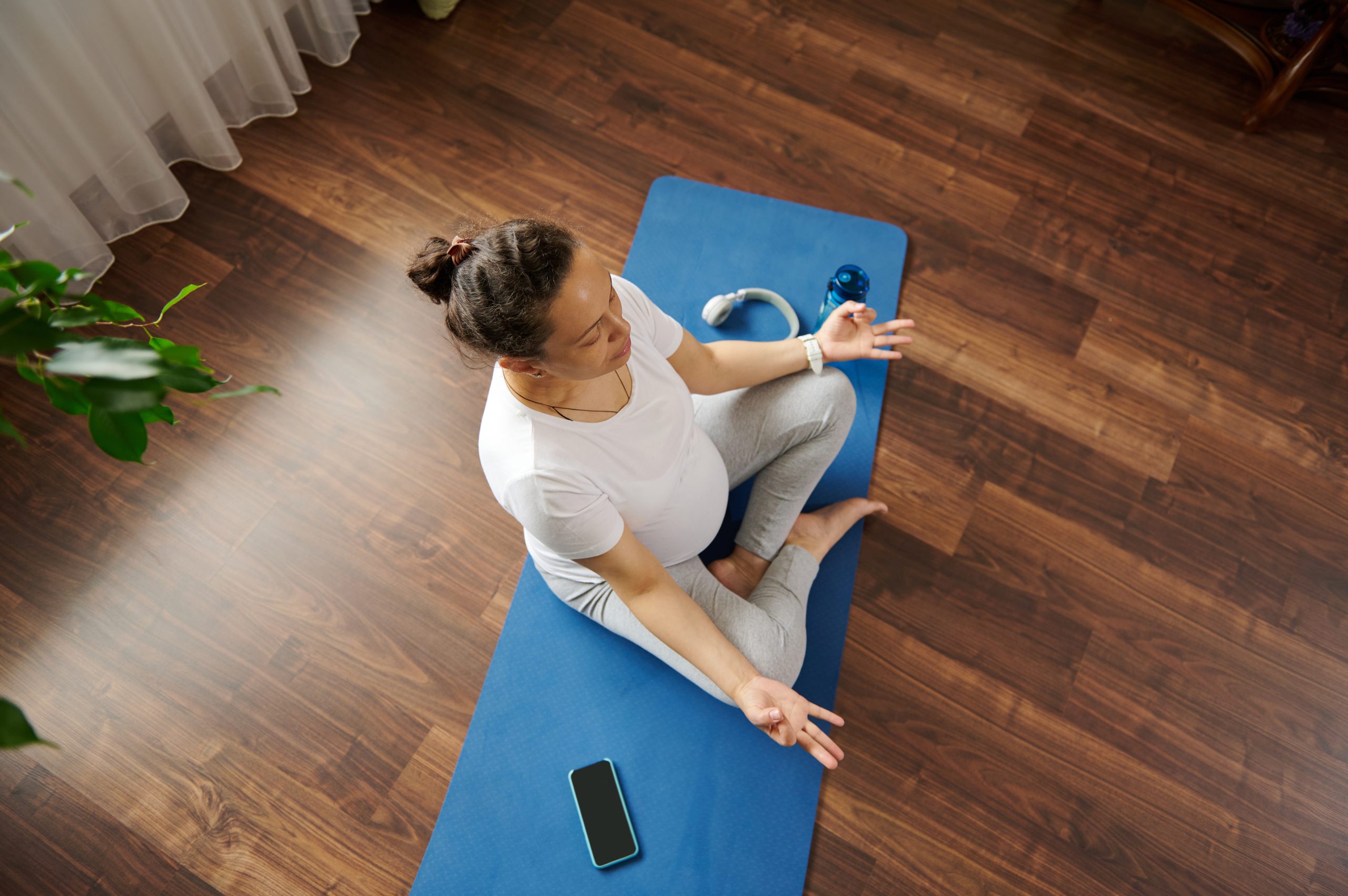 schwangere Frau meditiert auf Yogamatte